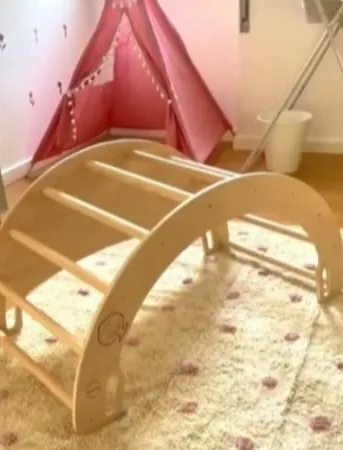 Arco de Pikler num quarto, ao lado de uma tenda de brincar