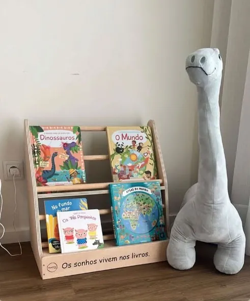 Estante Montessori com livros infantis e a frase «Os sonhos vivem nos livros» gravada