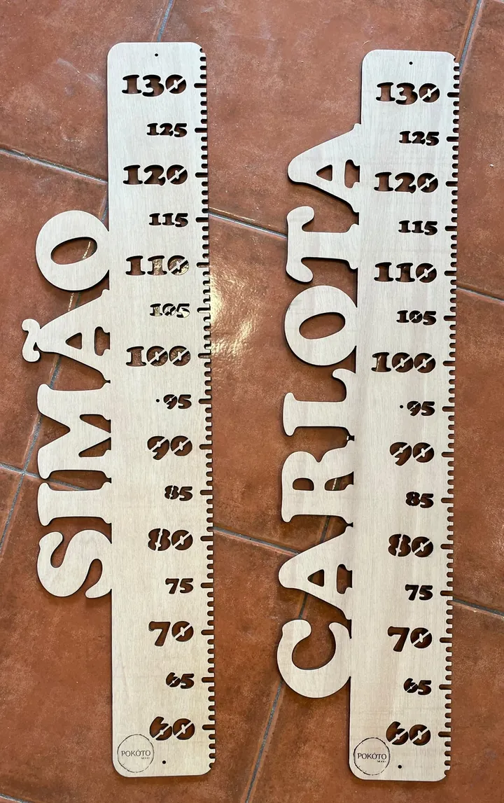 Duas réguas de crescimento com os nomes Simão e Carlota, pousadas no chão
