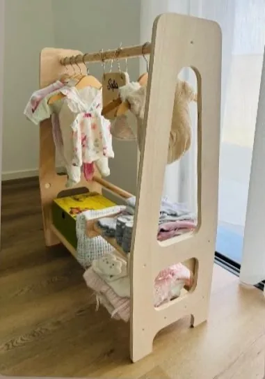 Roupeiro Montessori visto de lado, com roupa pendurada e uma prateleira em baixo